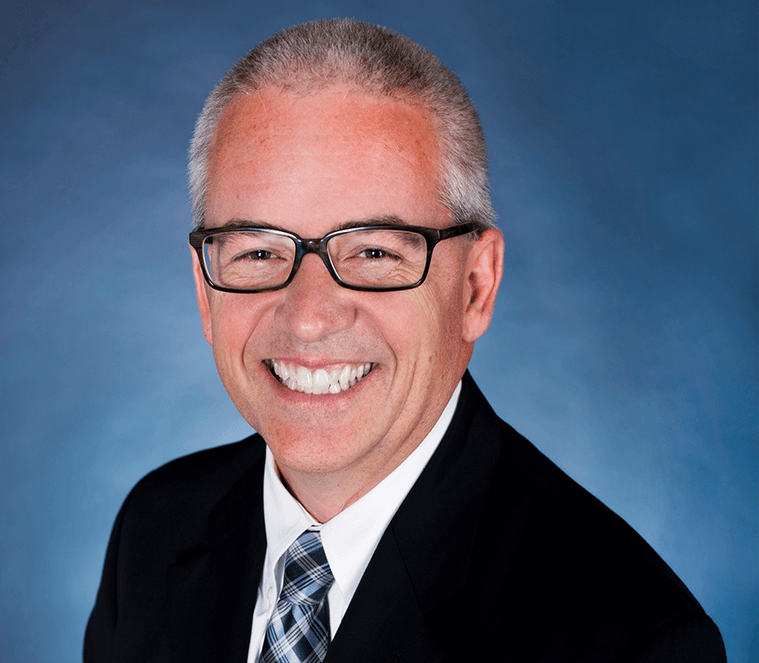 Man in black suit and glasses smiling