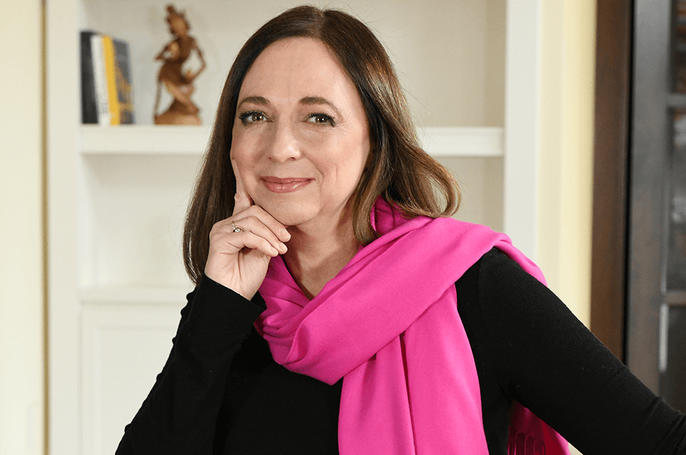 Woman in black shirt and long pink scarf posing in chair