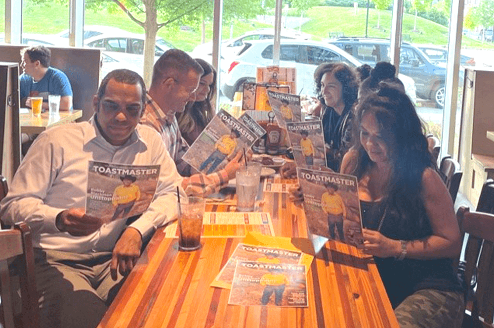 Group of people sitting at table looking at magazine