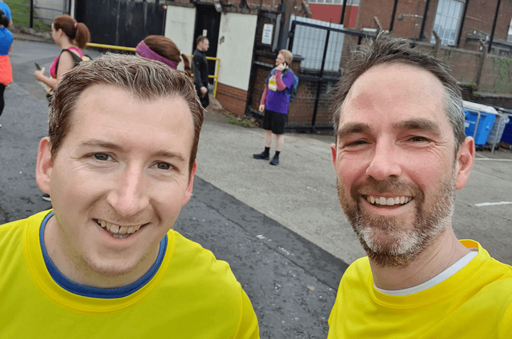 Two men in yellow shirts smiling after marathon