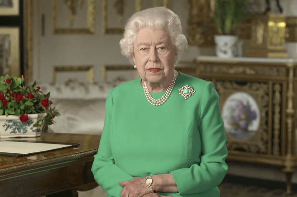 Queen Elizabeth II wearing green dress sitting in a chair speaking