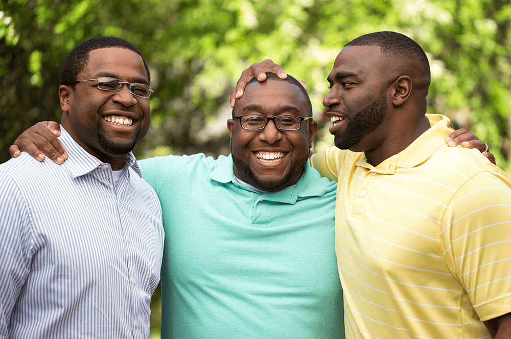Three male friends in different colored shirts posing together
