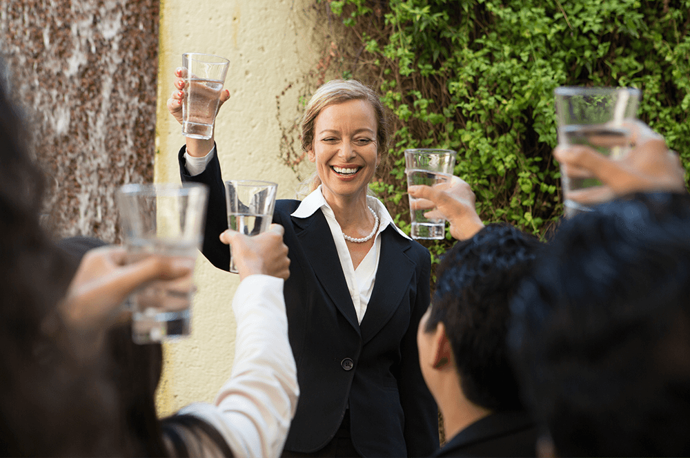 Woman holding up glass to toast with others