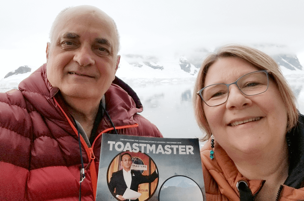 Man and woman holding magazine while on cruise along Antarctic Peninsula