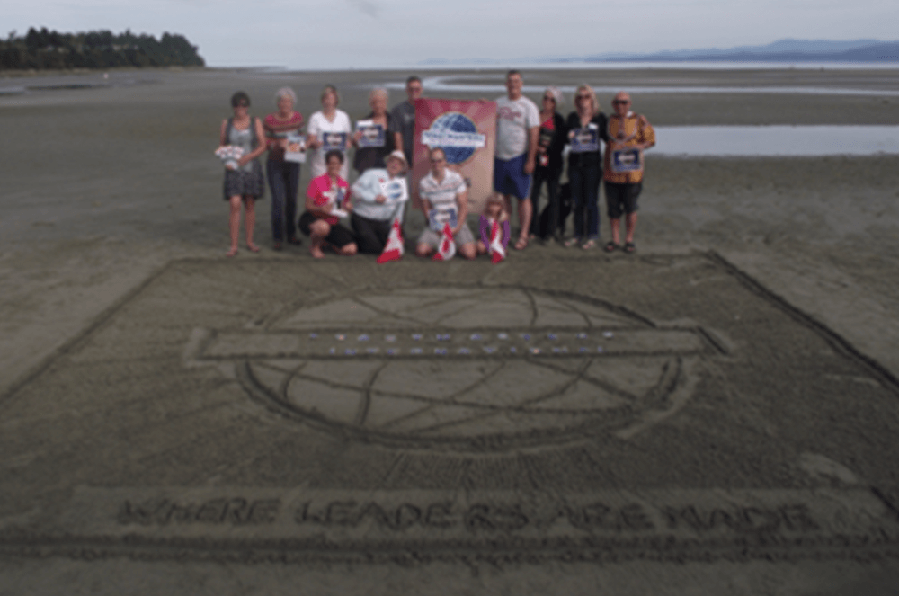 Members of the Arbutus Toastmasters club in Parksville, British Columbia, Canada, gathered at dawn—when the tide on Parksville Beach was at its lowest—to draw the Toastmasters logo in the sand.