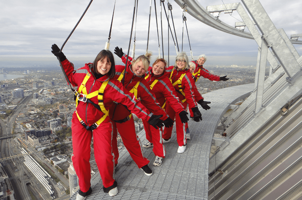 From rear to front: Toastmasters Mary Wallace, Sandy Robb, and Phyrne Parker, DTM, of Toronto, Canada, suit up with members of their walking club to take the 150-meter EdgeWalk trek around the roof of the CN Tower in Toronto, the tallest free-standing structure in the Western Hemisphere. 