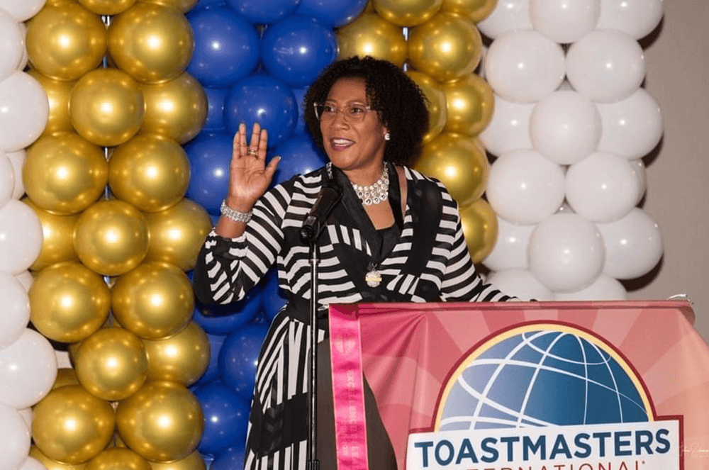 Rolle speaks from the lectern to fellow Toastmasters during an event.