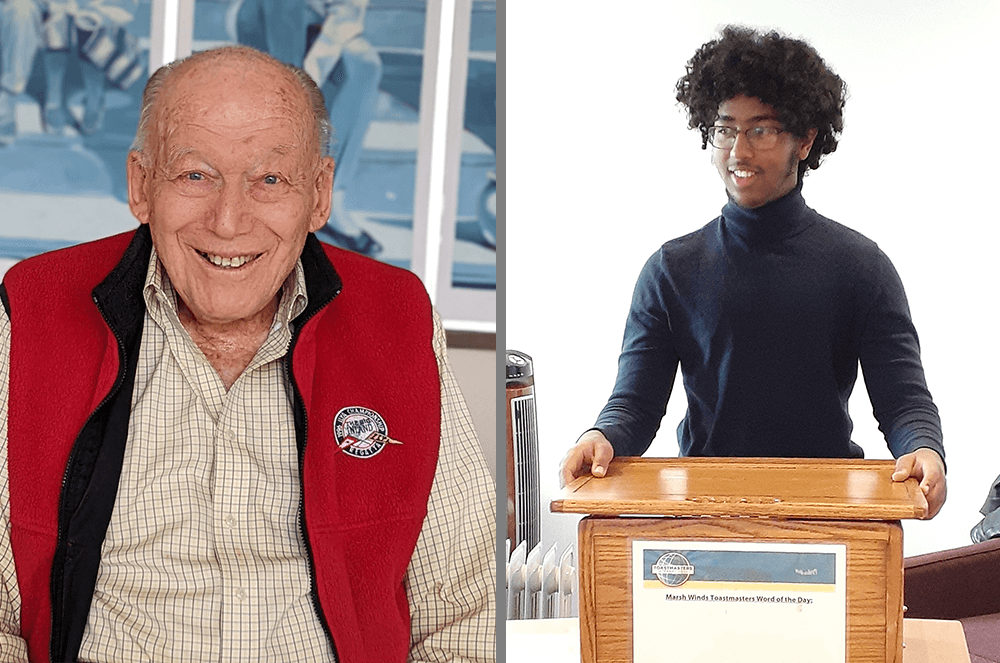 Ninety-six-year-old man smiling in red vest and eighteen-year-old man in blue turtleneck standing at lectern  