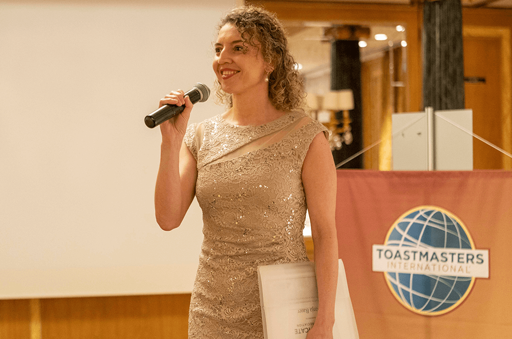 Woman in gold dress speaking into microphone
