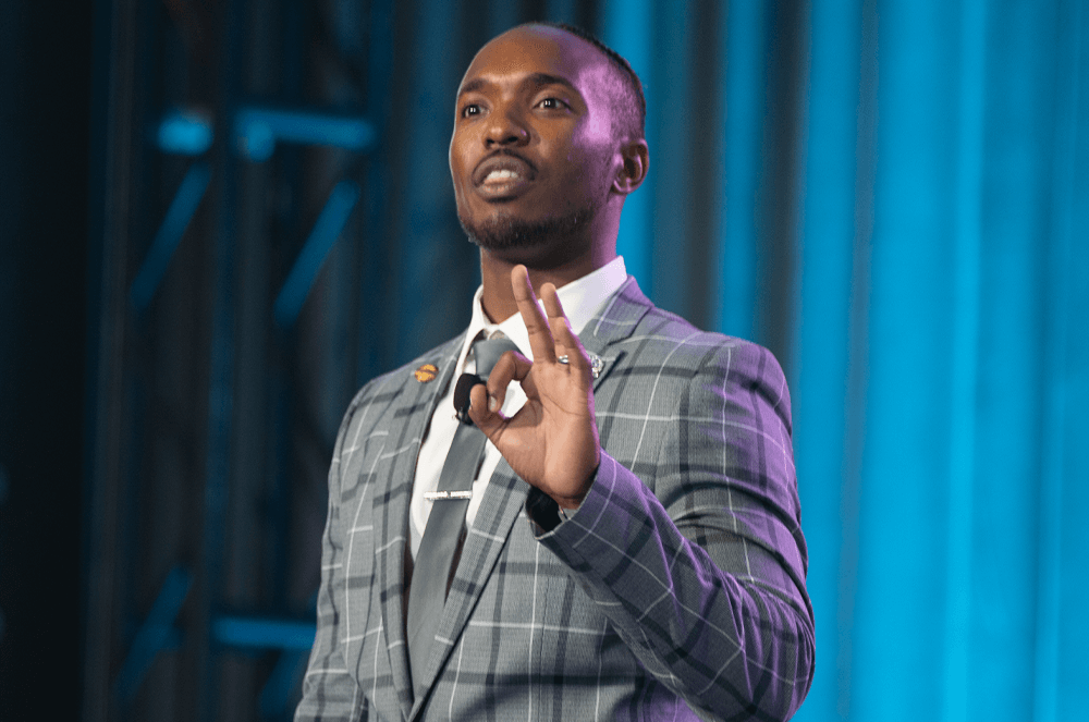 Man speaking onstage using hand gesture