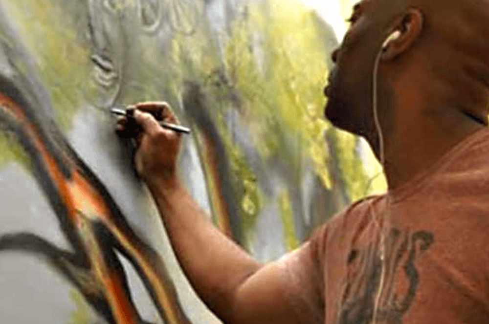 Man wearing headphones while painting on a canvas