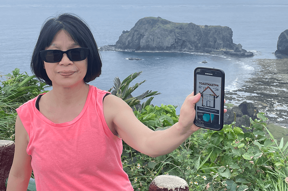 Woman in pink shirt holding up digital magazine with on island in Taiwan