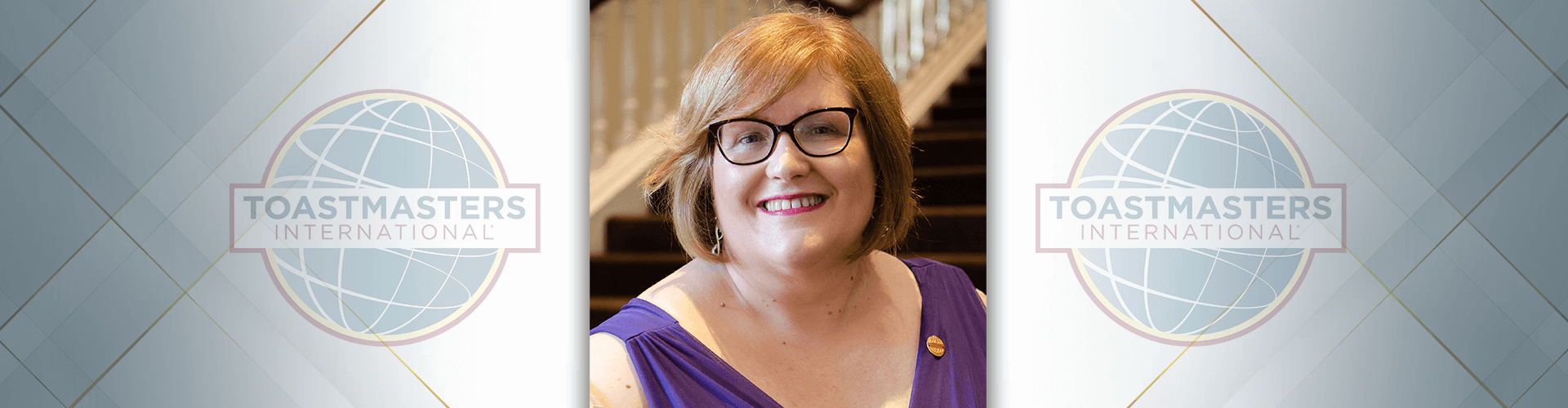 Toastmasters International President Morag Mathieson smiling in purple dress and gold pin