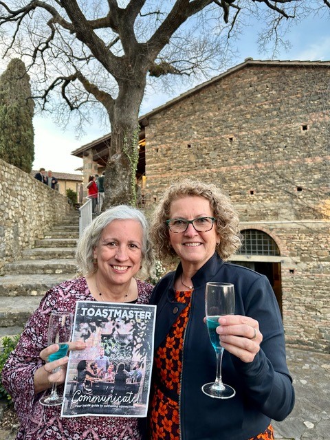 Two women posing in Italy holding magazine and drink