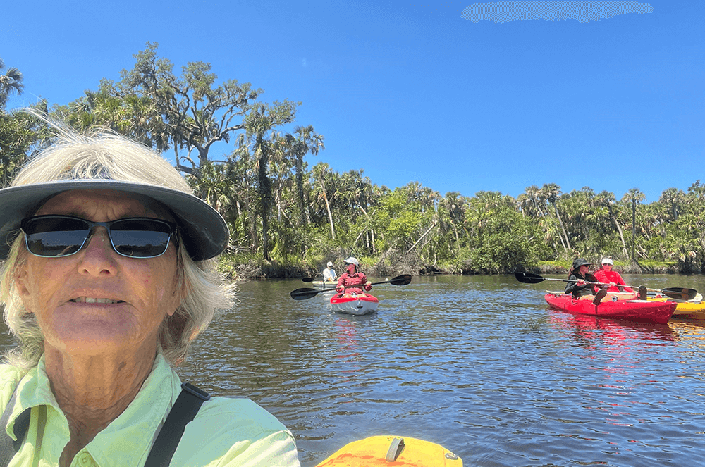 Female tour guide on yellow canoe with other canoers on water in background