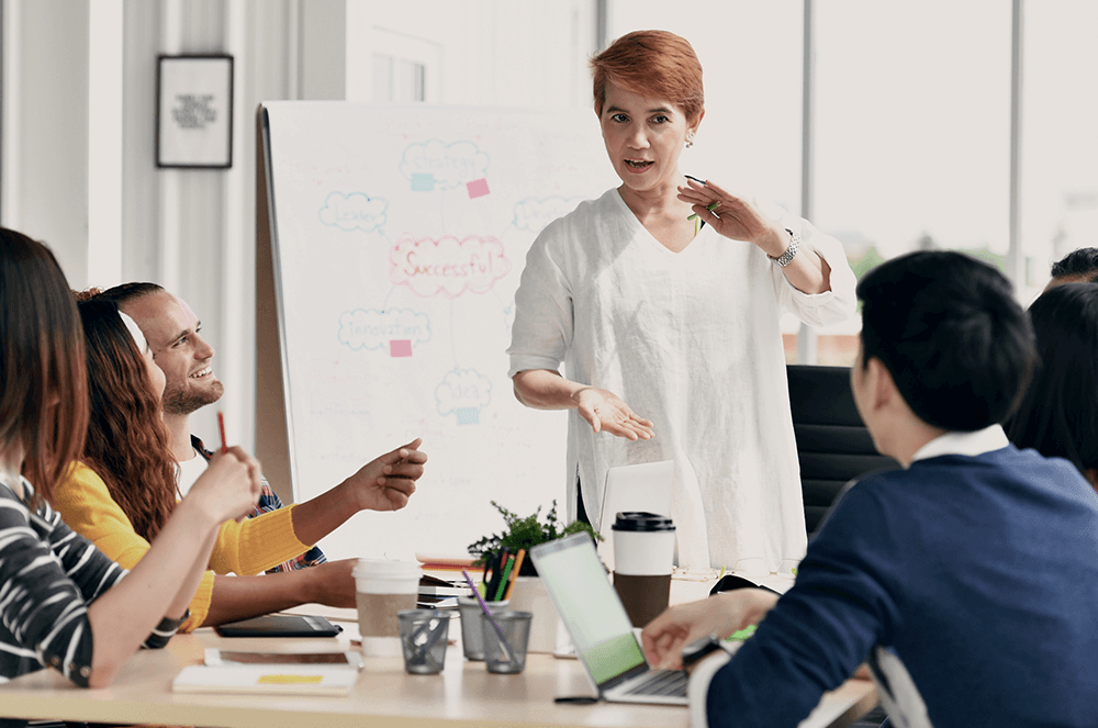 Woman in white shirt using hand gestures during work presentation to coworkers