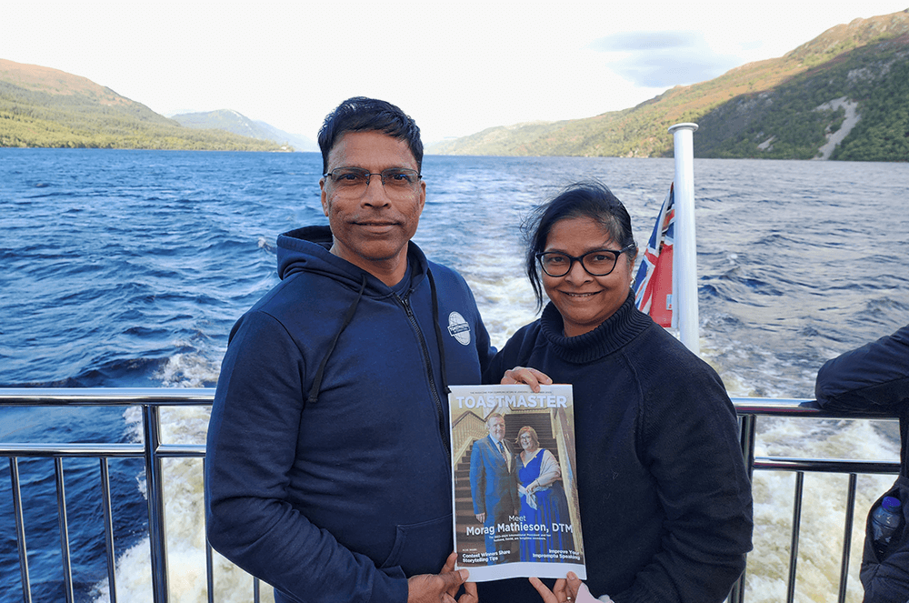 Man and woman holding magazine cover while on boat at Loch Ness lake
