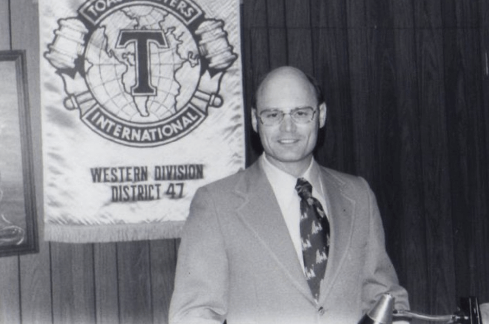 Black and white image of man with old Toastmasters banner