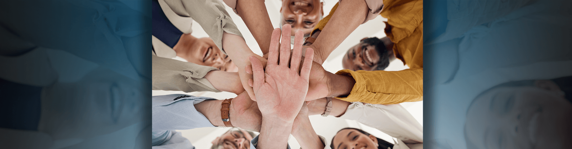 Group of people looking down with hands stacked together