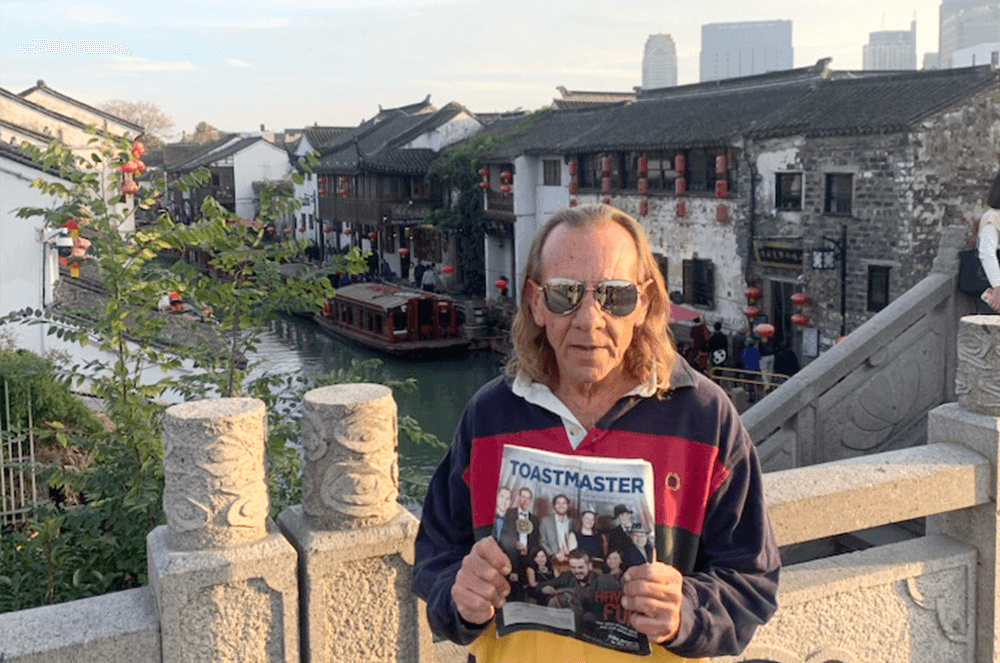 Man holding Toastmaster magazine outdoors in Suzhou, Jiangsu, China