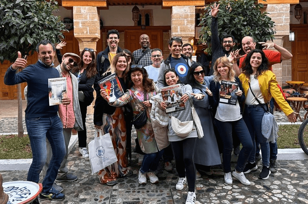 Group of people posing outdoors while holding magazines