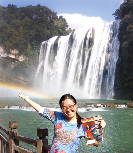 Aurore Liang, ACB, CL, from Montreal, Quebec, Canada, stands in front of the Huangguoshu Waterfall in China.