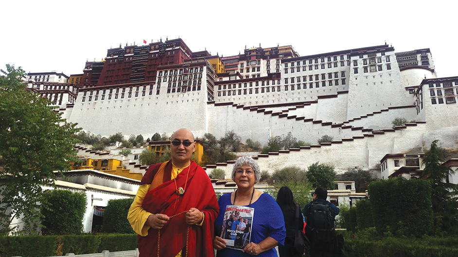Arlene Jayme, DTM, from Palm Bay, Florida, stands with a monk in front of Potala Palace in Lhasa, Tibet.