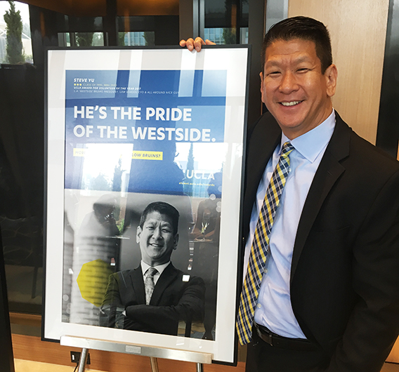 A well-liked teacher and mentor in the UCLA community, Yu poses next to a poster of himself after being recognized with the UCLA Alumni Volunteer of the Year Award.