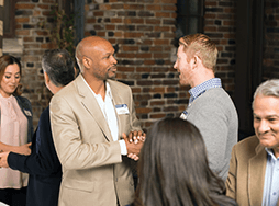 Two men shaking hands at a Toastmasters Open House