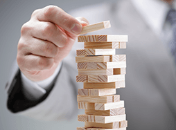 Hand setting wooden block on Jenga pile