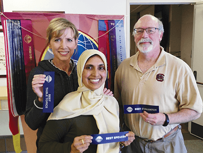 Heidi Swan, Bilquis Ahmed and Ron Maroko pose with Toastmasters ribbons