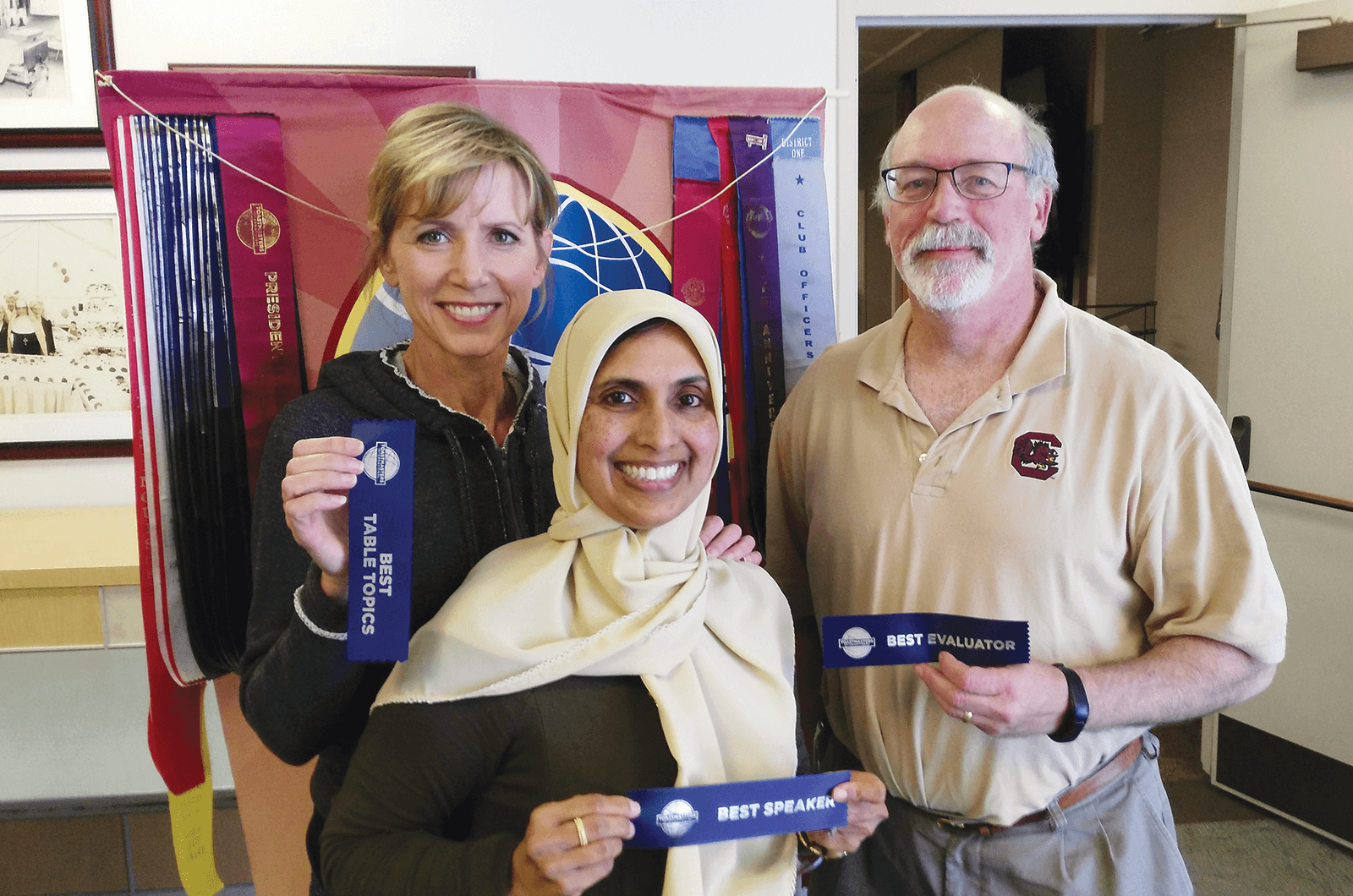 Heidi Swan, Bilquis Ahmed and Ron Maroko pose with Toastmasters ribbons at a Torrance Chamber of Commerce club meeting in California.