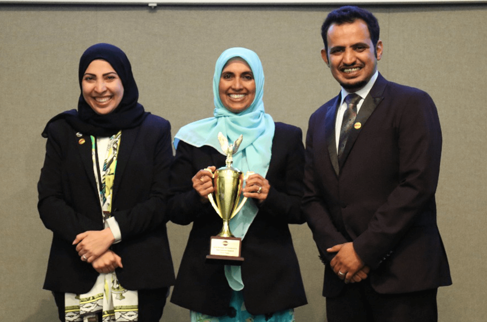 Bilquis proudly holds up a trophy while standing next to 2015 World Champion of Public Speaking Mohammed Qahtani in Saudi Arabia in 2018.