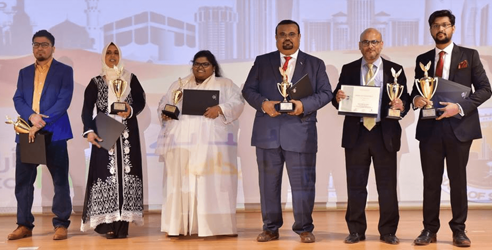 Bilquis (second from left) holds her trophy onstage after winning at the District 79 speech contest in 2018.