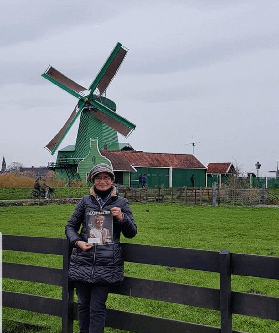 Mary Ai You Ting of Kuching, Malaysia, visits Zaanse Schans, a neighborhood in Zaandam, Holland, where historic windmills and distinctive green wooden houses were relocated to recreate the look of an 18th-century village.