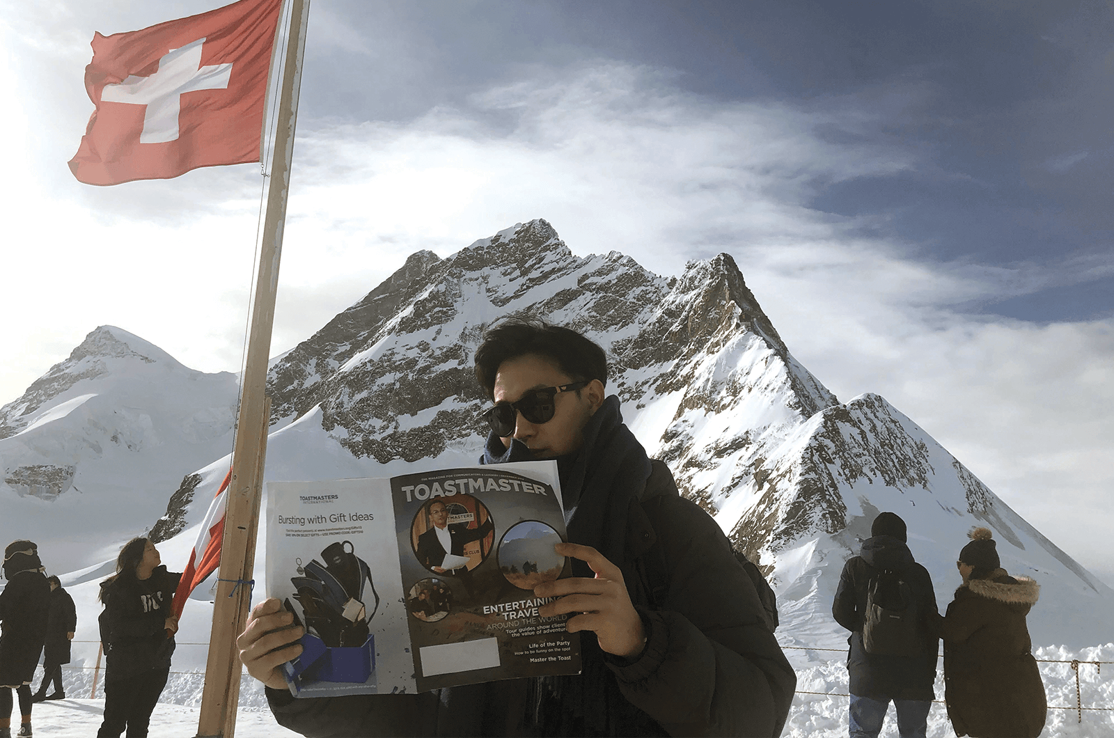 Byungjoo Lee of Seongnam, Korea, reads his Toastmaster in front of Jungfrau, one of the highest summits in the Bernese Alps of western Switzerland.