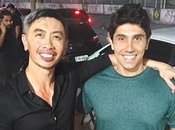 Man in black shirt poses with man in green shirt