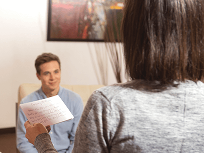 Woman with notecard speaking to man