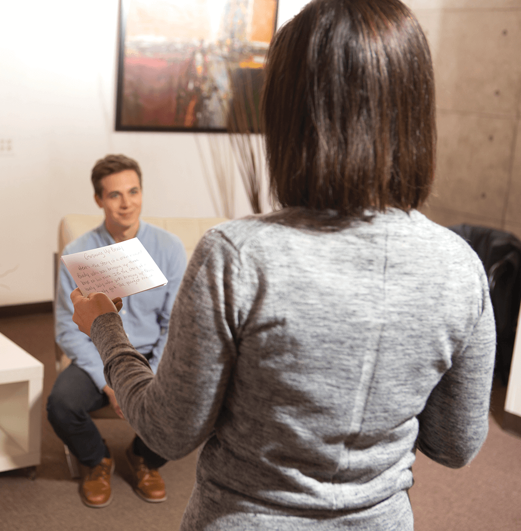 Woman with notecard speaking to man