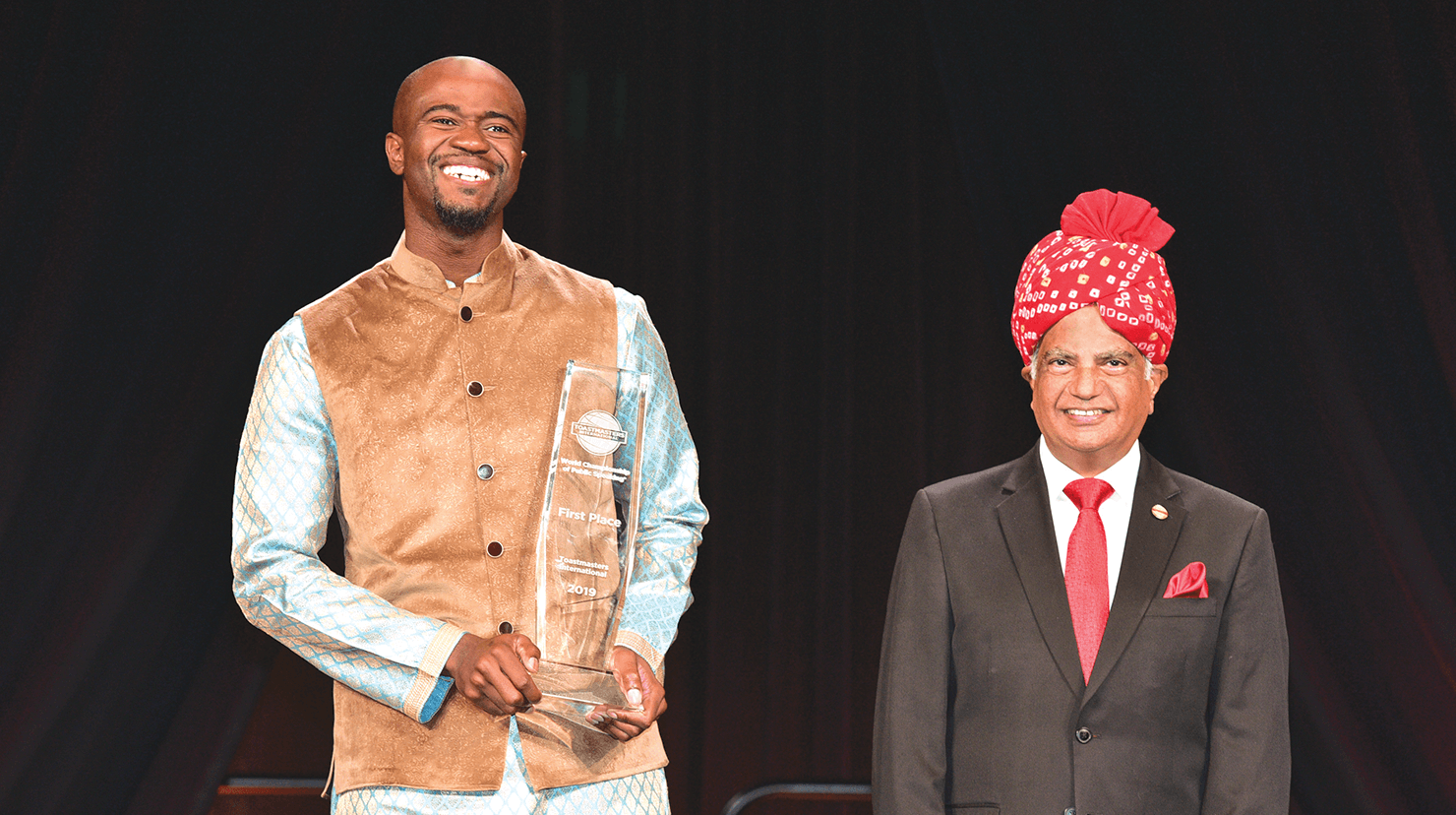 Beverly reacts happily after being announced by International President Deepak Menon (right) as the 2019 World Champion of Public Speaking.