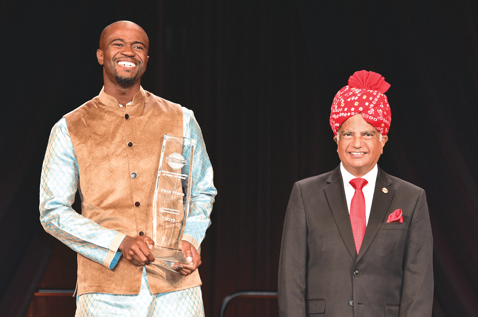 Beverly reacts happily after being announced by International President Deepak Menon (right) as the 2019 World Champion of Public Speaking.
