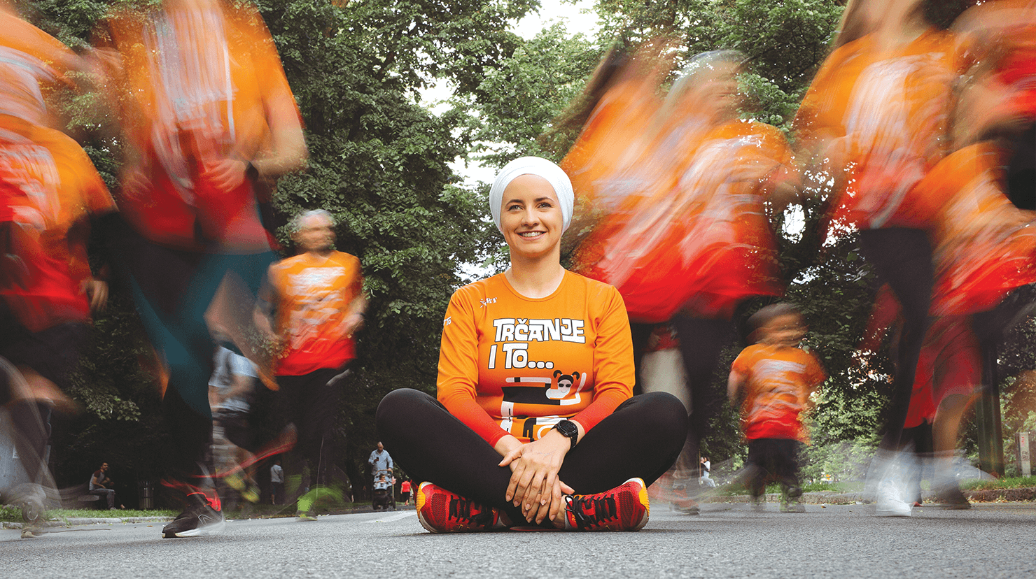 Woman in orange shirt sitting on pavement 