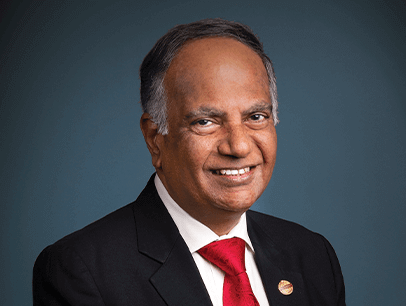 Toastmasters International President Deepak Menon in suit and red tie