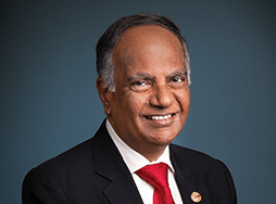 Toastmasters International President Deepak Menon in suit and red tie