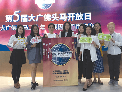 Group of Toastmasters holding club banner and signs