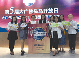 Group of Toastmasters holding club banner and signs