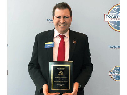 Thomas Iland poses with Toastmasters plaque