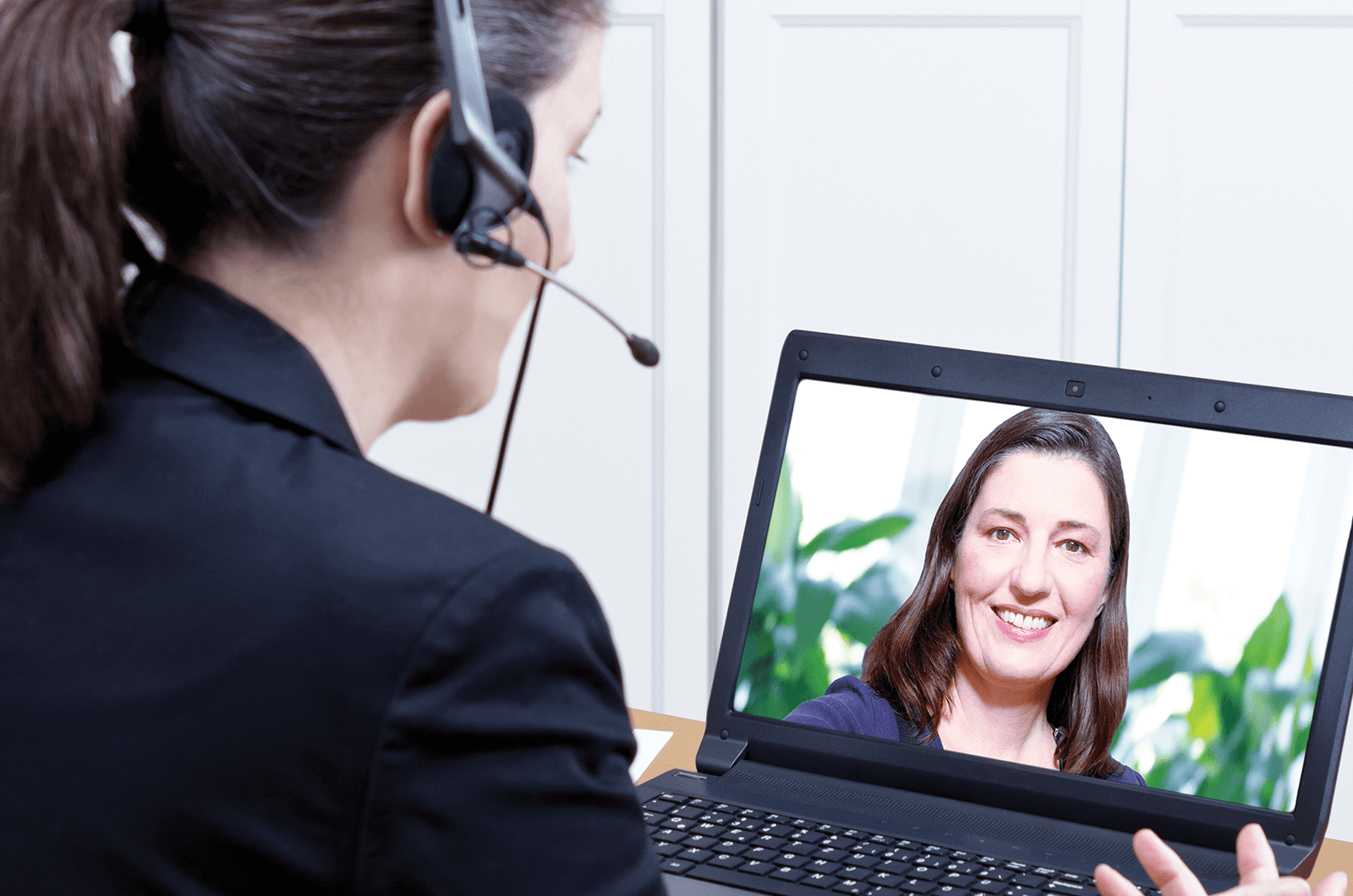 Woman wearing headset interviewing with another woman on laptop
