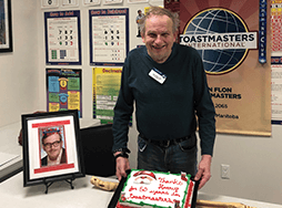 Man posing with banner and cake