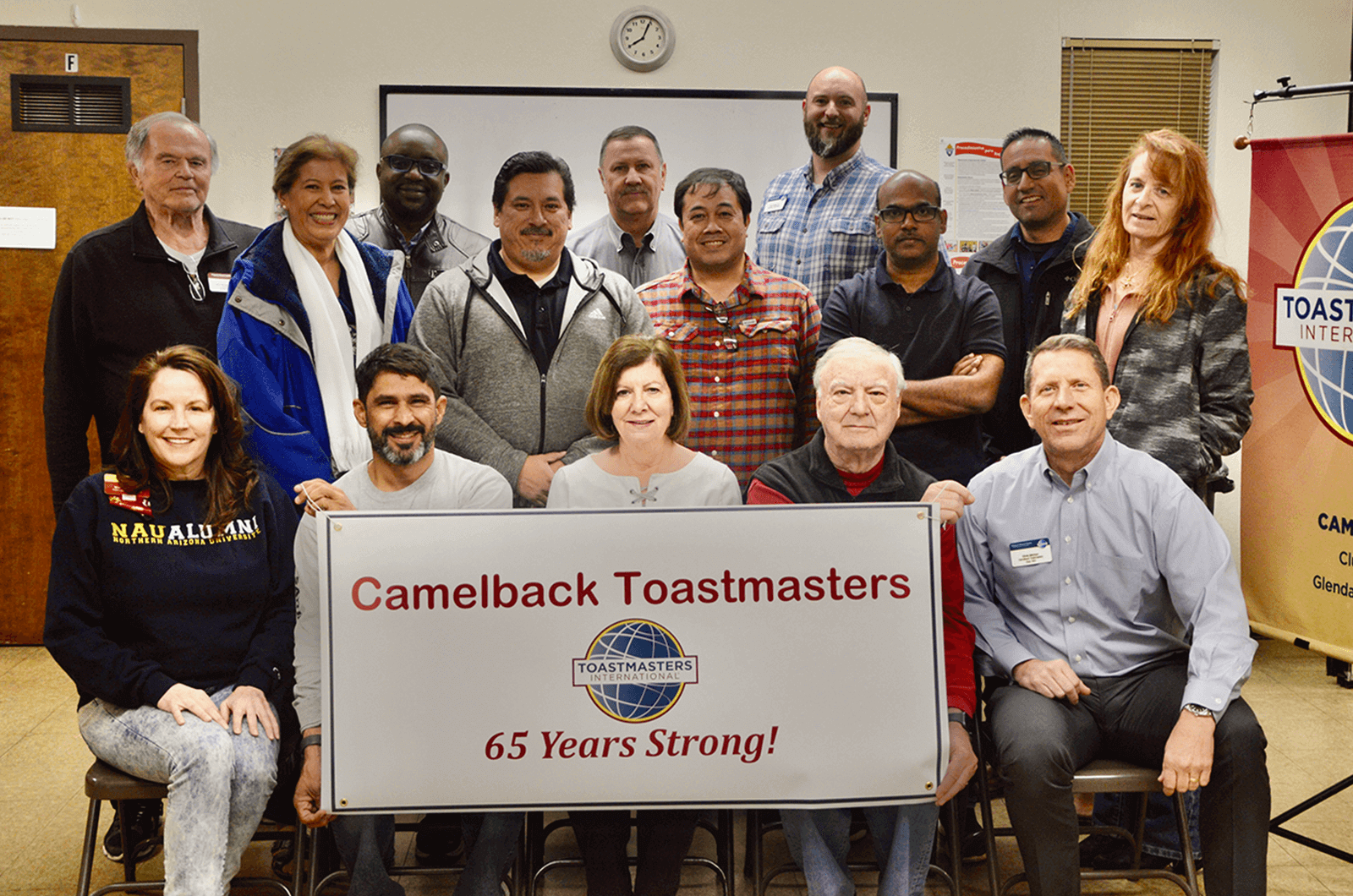 Members of Toastmasters club hold up sign with club name